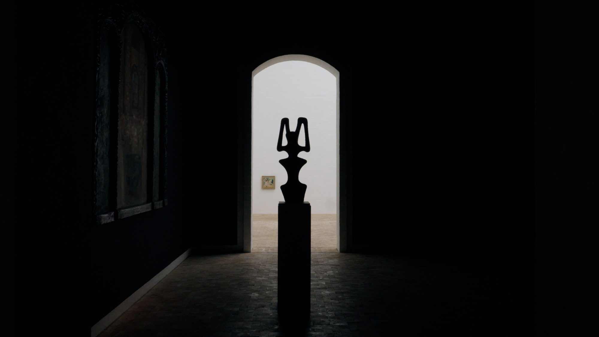 A sculpture in silhouette in a lit doorway