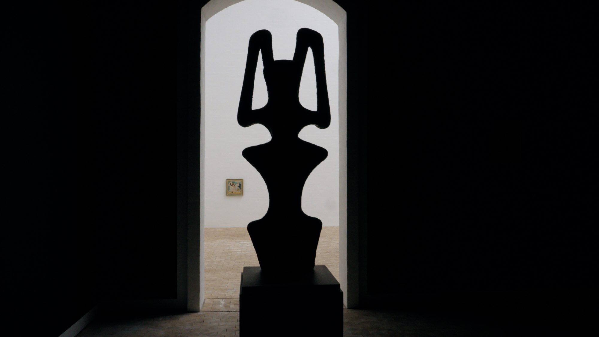 A sculpture in silhouette in the arch of a door