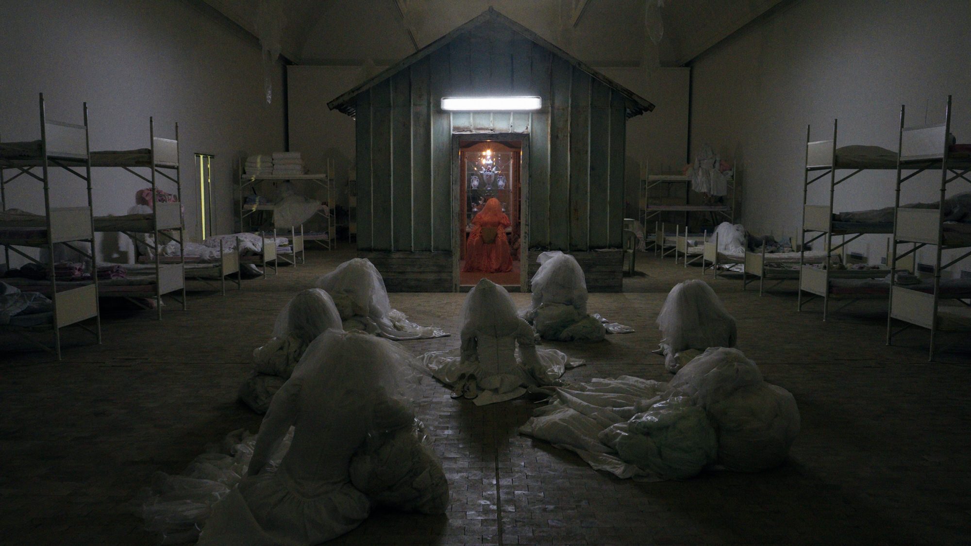 SIGNA, the dormitory hall with bunk beds, veiled figures on the floor and the shed at the centre