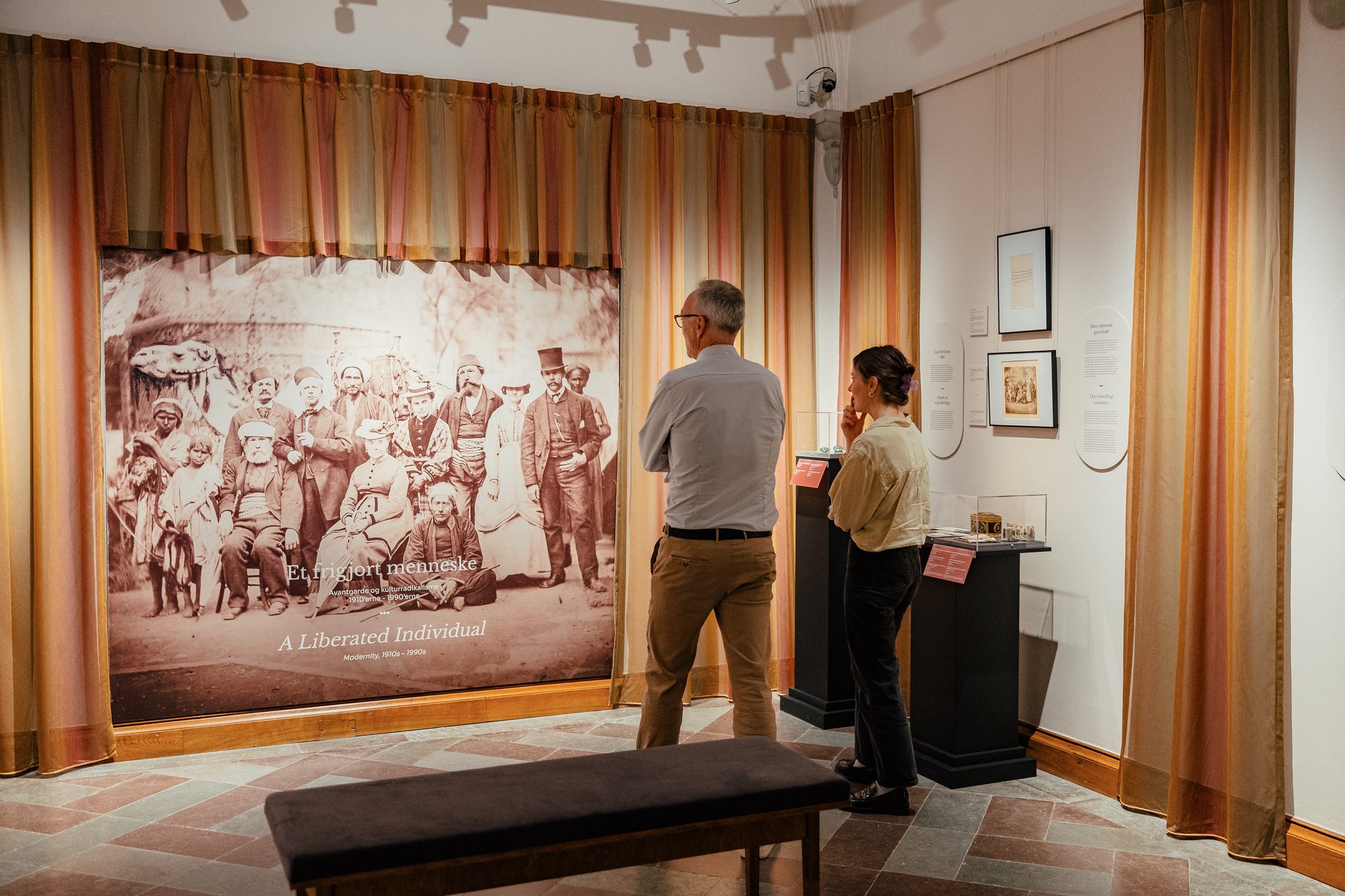 Danner af Danmark, visitors in front of a large historical photograph framed by curtains