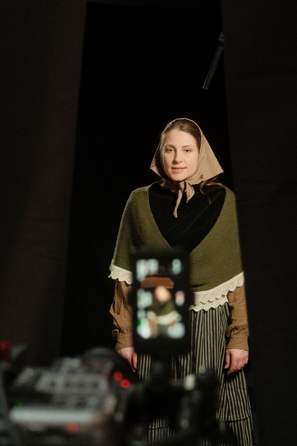 Behind the scenes, actress in shawl and headscarf seen past the camera