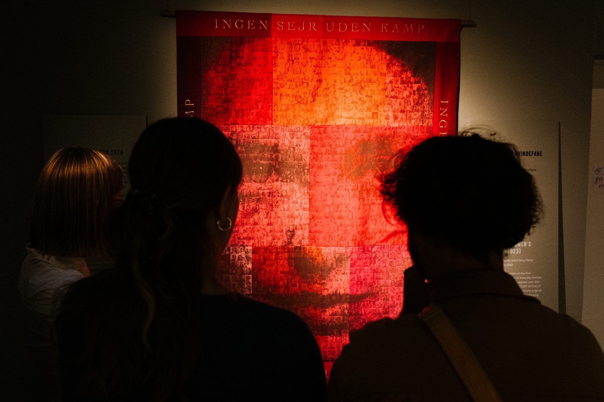 Kvindeliv, visitors in front of a red banner reading no victory without struggle
