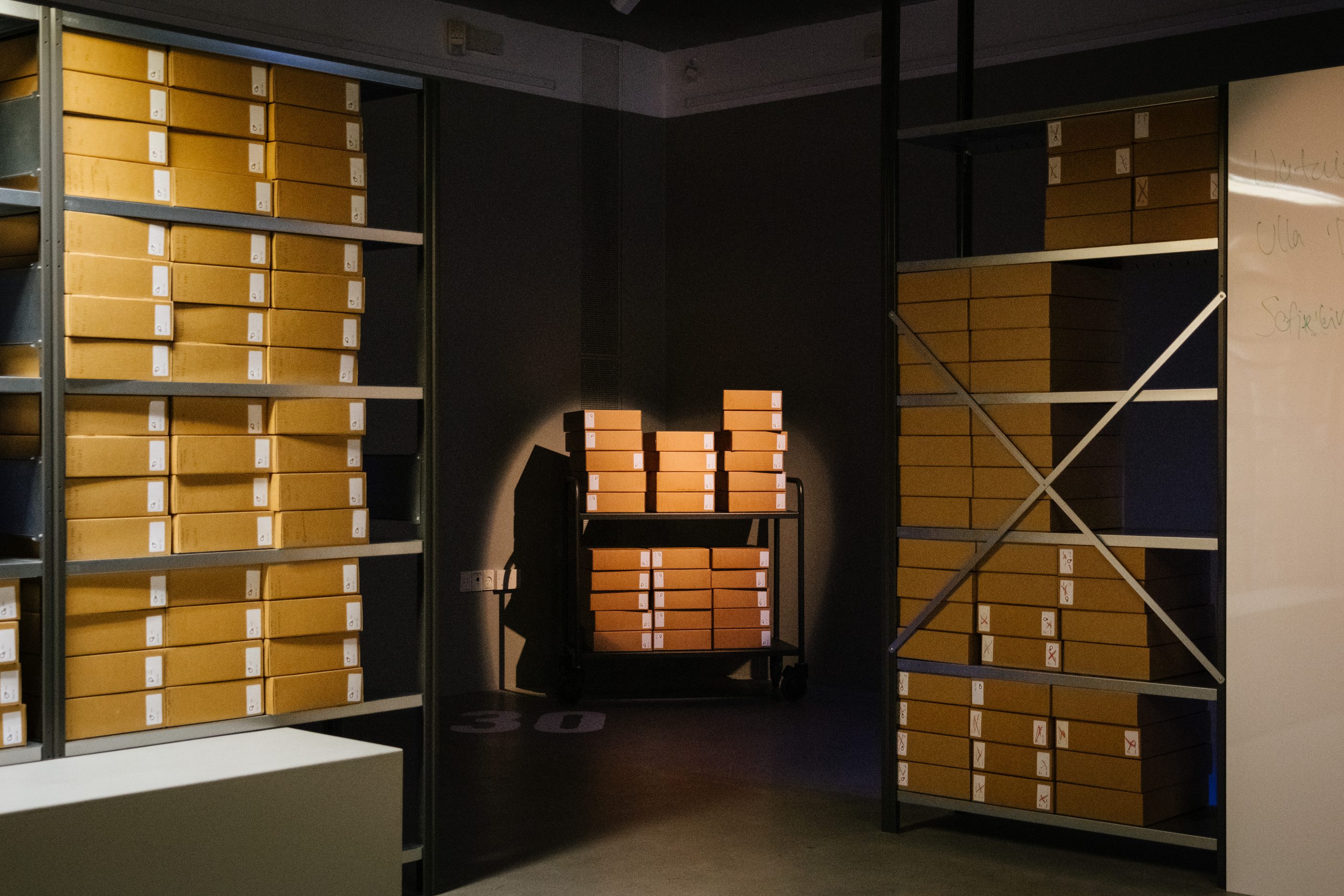 Kvindeliv, the opening room: a darkened reconstruction of the museum archive with shelves of boxes