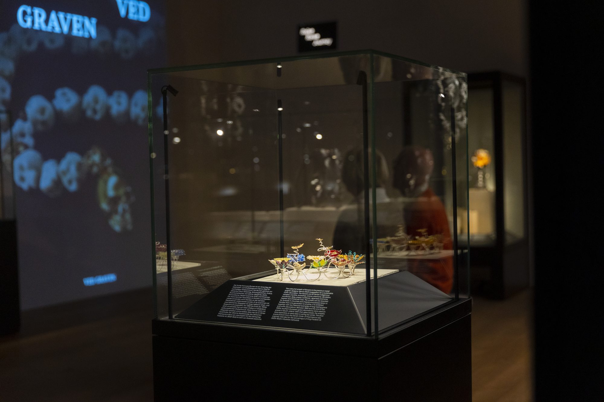 Makabre Mesterværker, vitrine of jewellery in front of the projection Ved graven