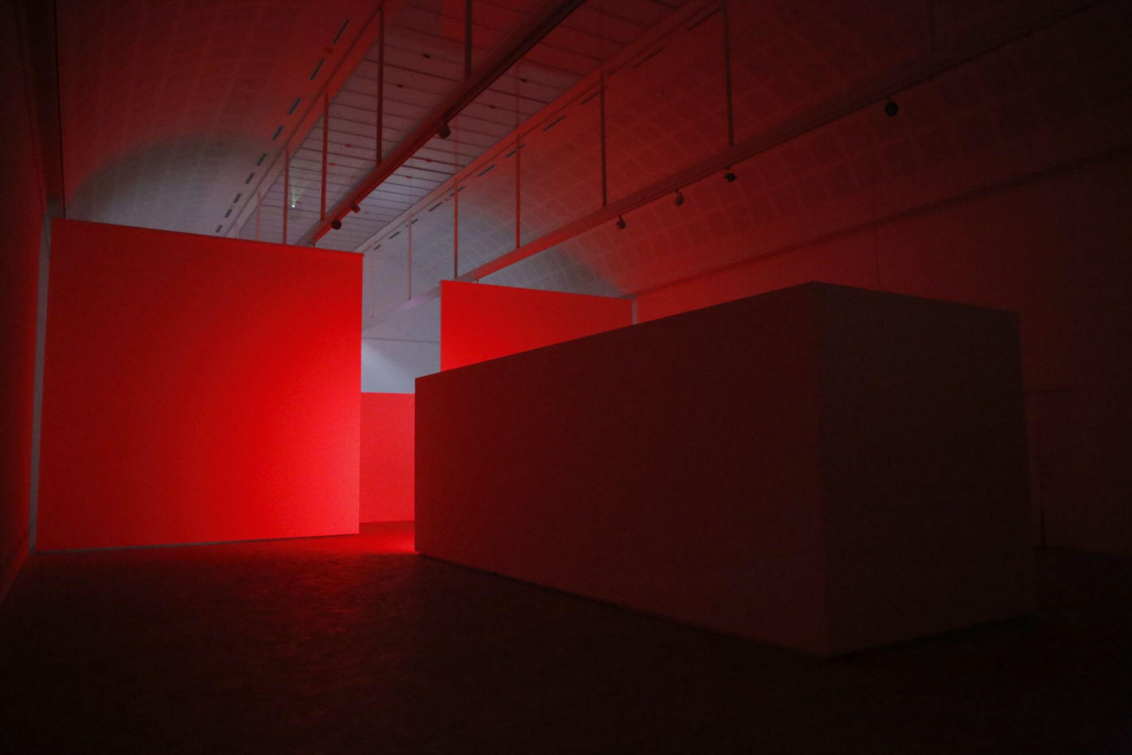 MELT, the white chamber lit red under the museum's timber roof