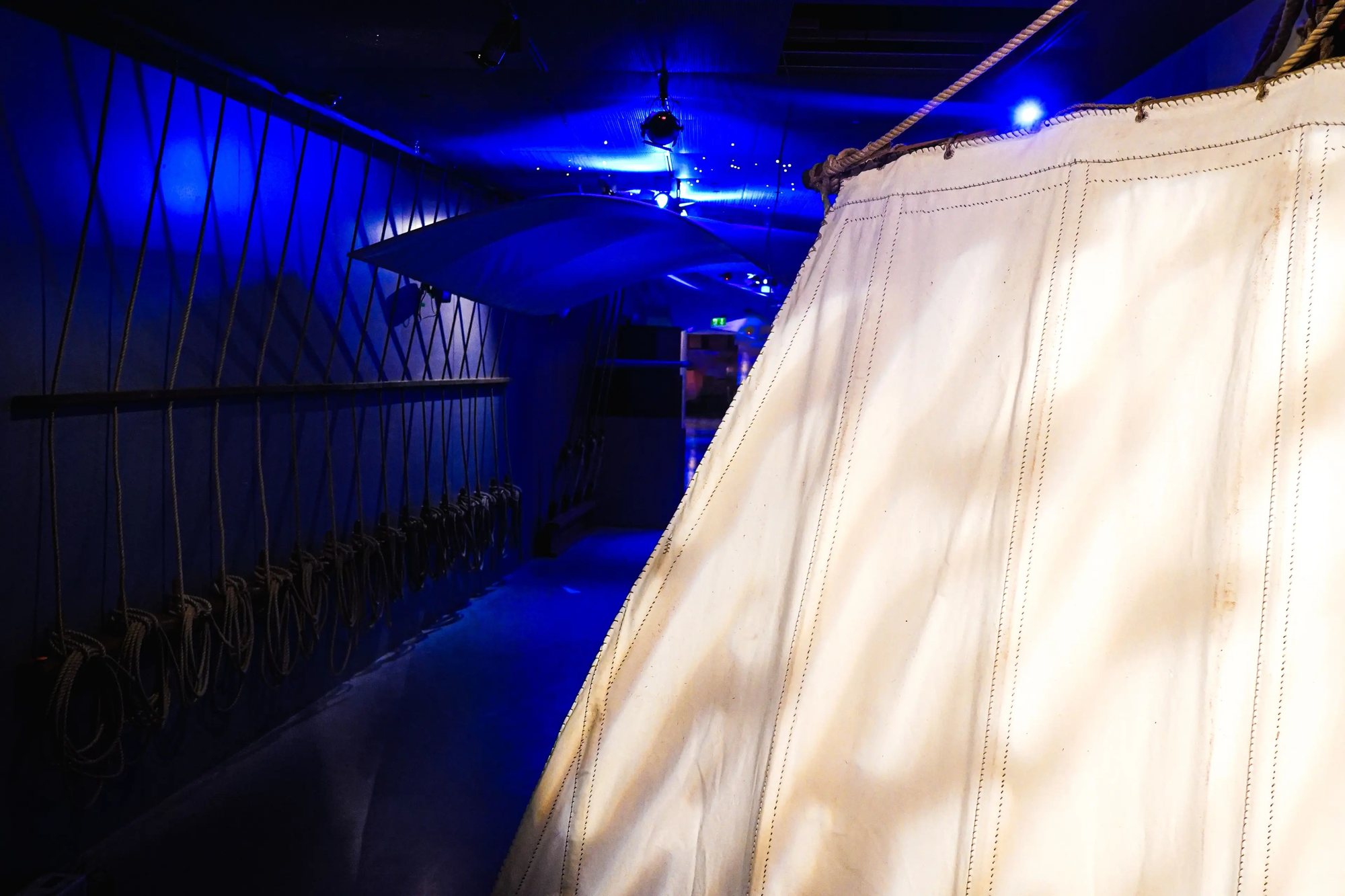 Søfarer, a lit sail in the blue passage with coiled ropes along the wall