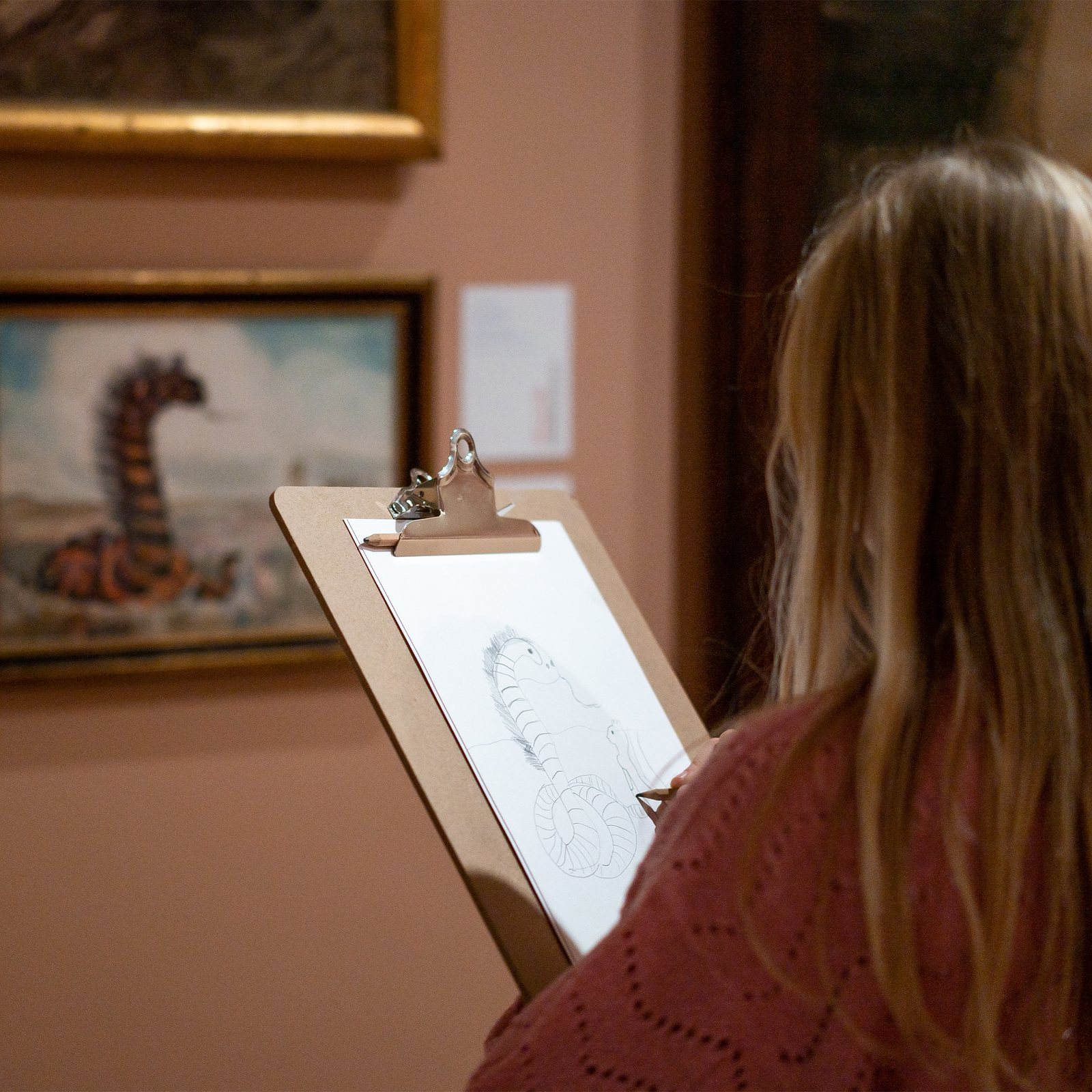 Tegn Amok, a visitor drawing a sea monster on a clipboard in front of the painting