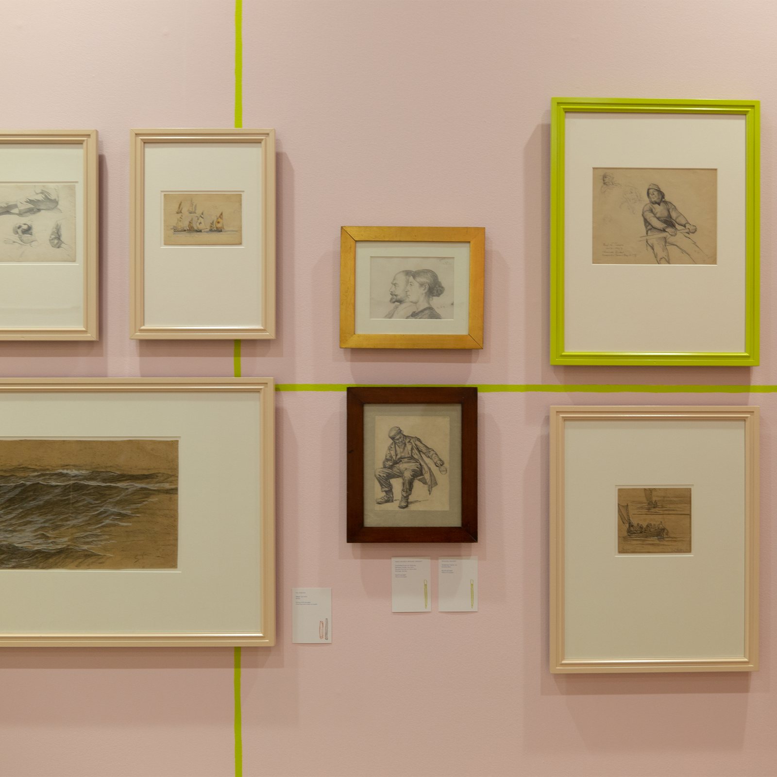 Tegn Amok, framed drawings on a pink wall hung from the yellow line