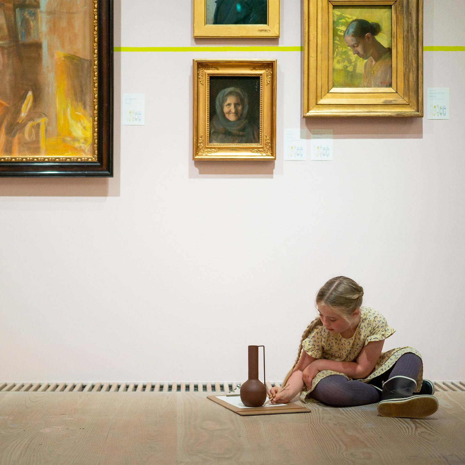 Tegn Amok, a girl drawing a vase on the floor under the portraits