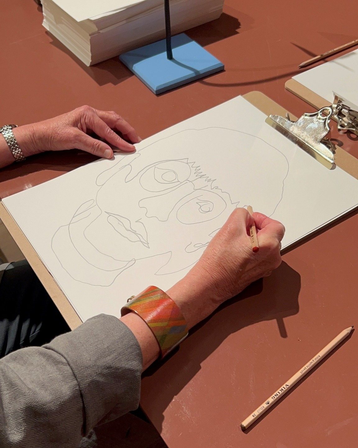 Tegn Amok, a hand drawing a portrait in pencil on a clipboard