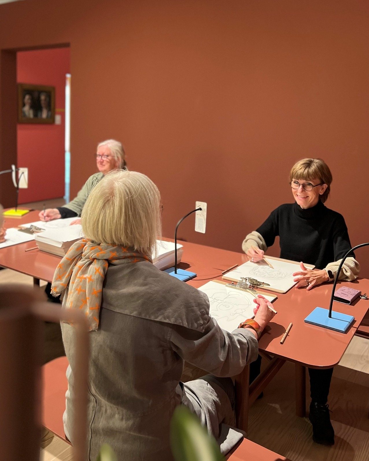 Tegn Amok, two visitors drawing at the table under the lamps